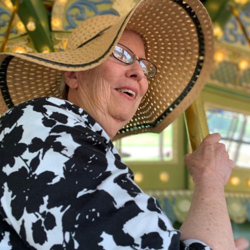 Dolan resident in sun hat riding a carousel